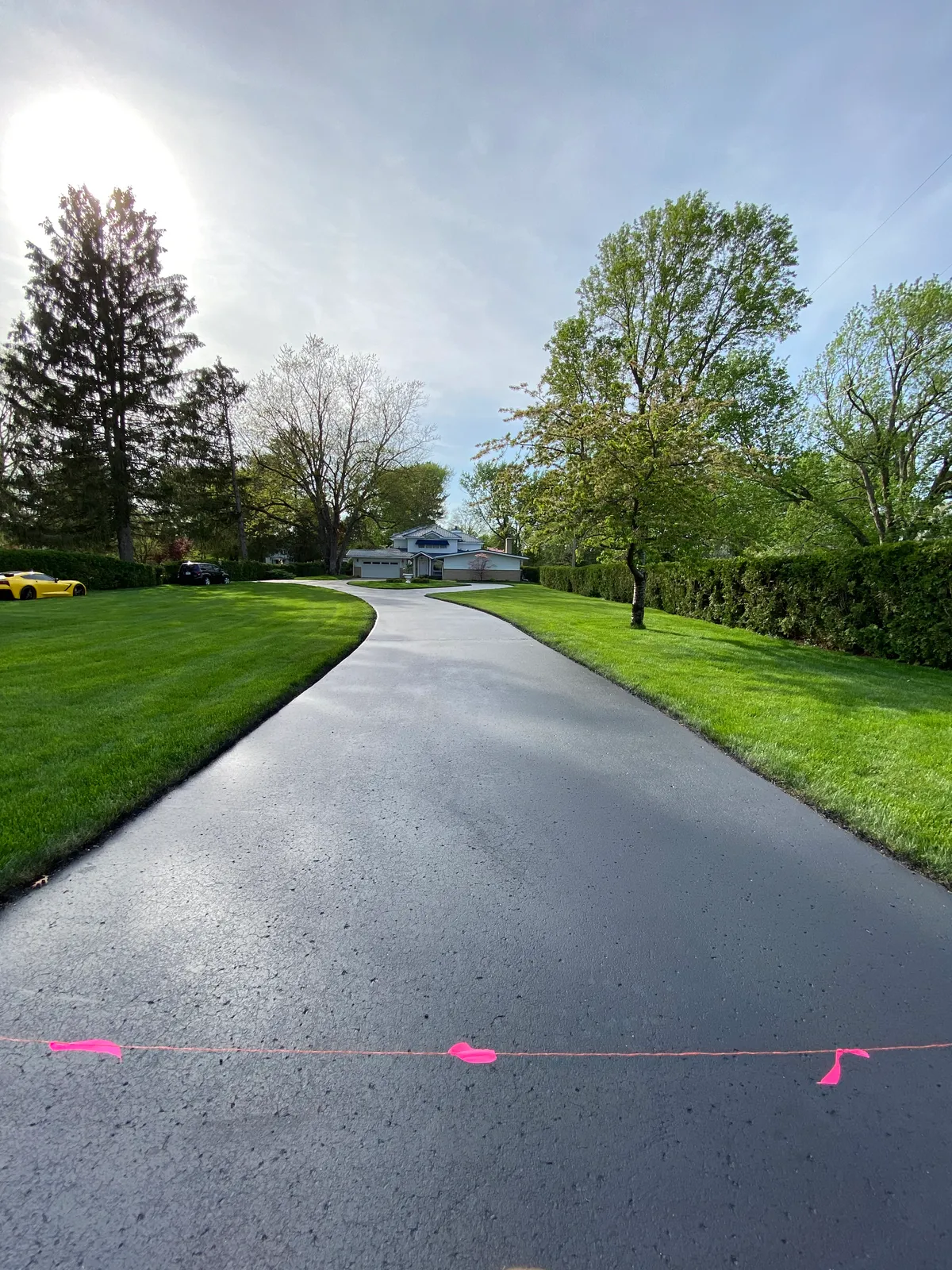 Smooth black sealcoated driveway bordered by green lawn